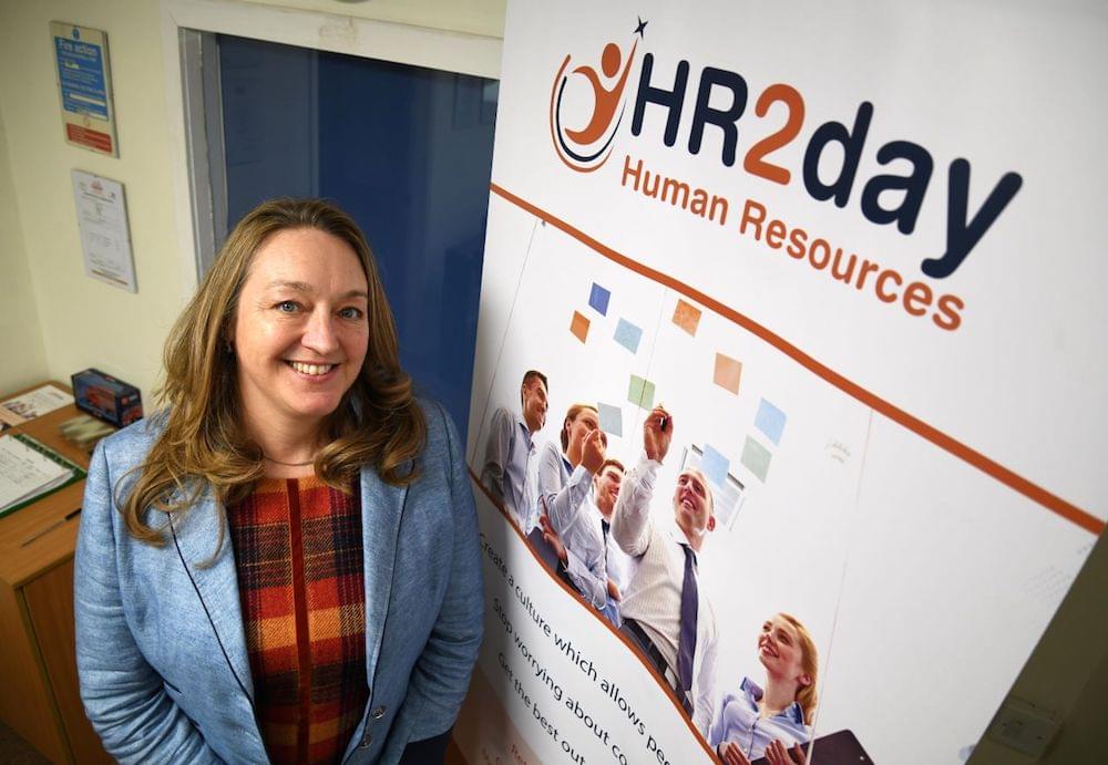 Nicky Jolley posing next to HR2day vertical banner in office